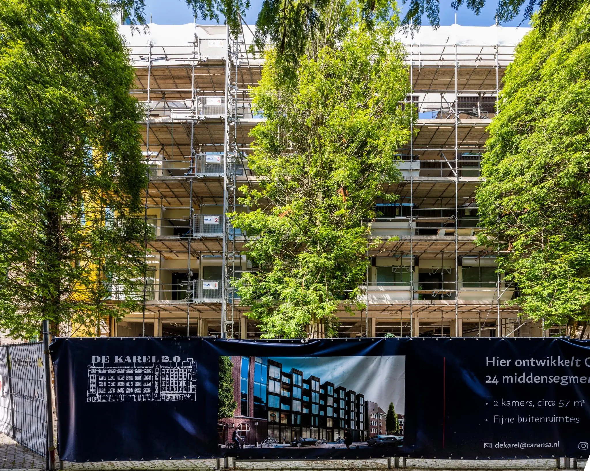 Appartementencomplex aan de Karel du Jardinstraat in Amsterdam in de steigers met bouwdoek waarop het nieuwbouwproject 'De Karel 2.0' wordt aangekondigd.